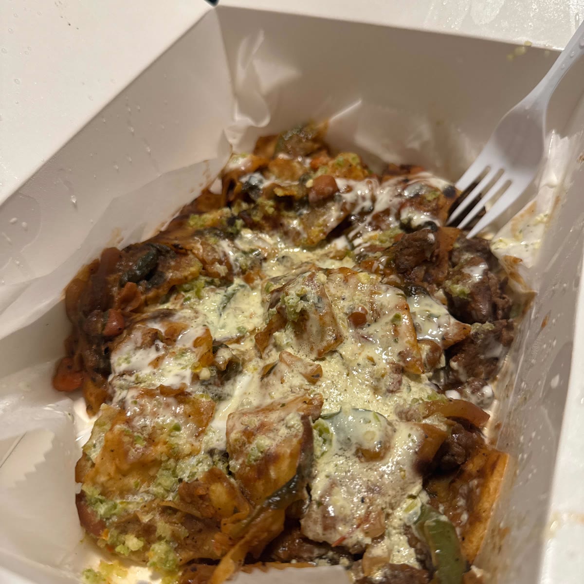 Beef KK in a takeout box with creamy sauce