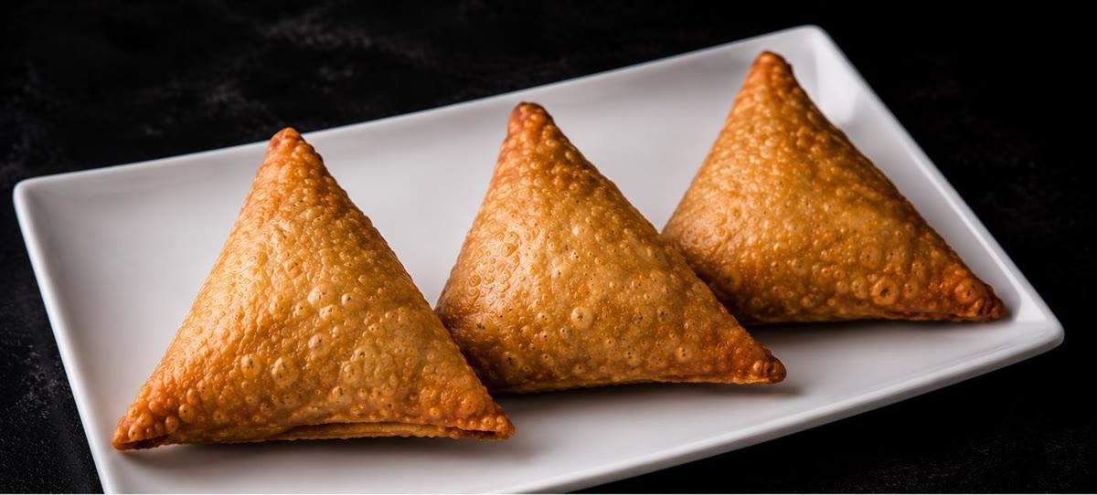 Three crispy beef sambusas on a white plate